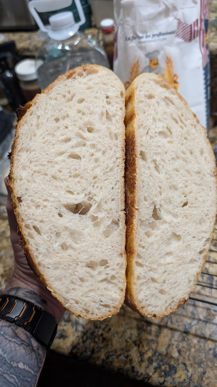 Sliced sourdough boule showing an open, airy crumb and crisp crust